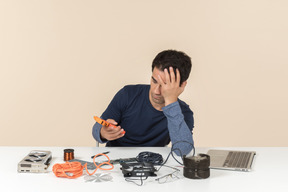 A young man in casual blue clothes working with computer details