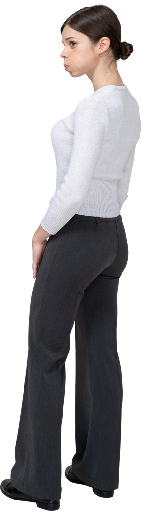 Three-quarter back view of a young woman in office clothing blowing cheeks