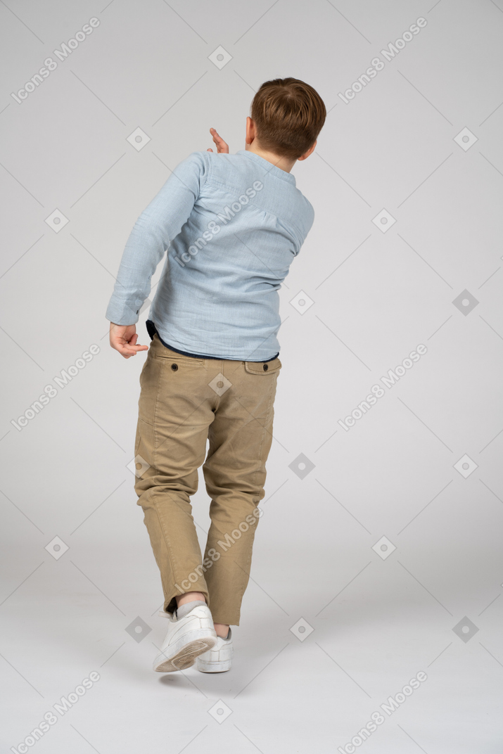 Back view of a boy in a blue shirt and khaki pants