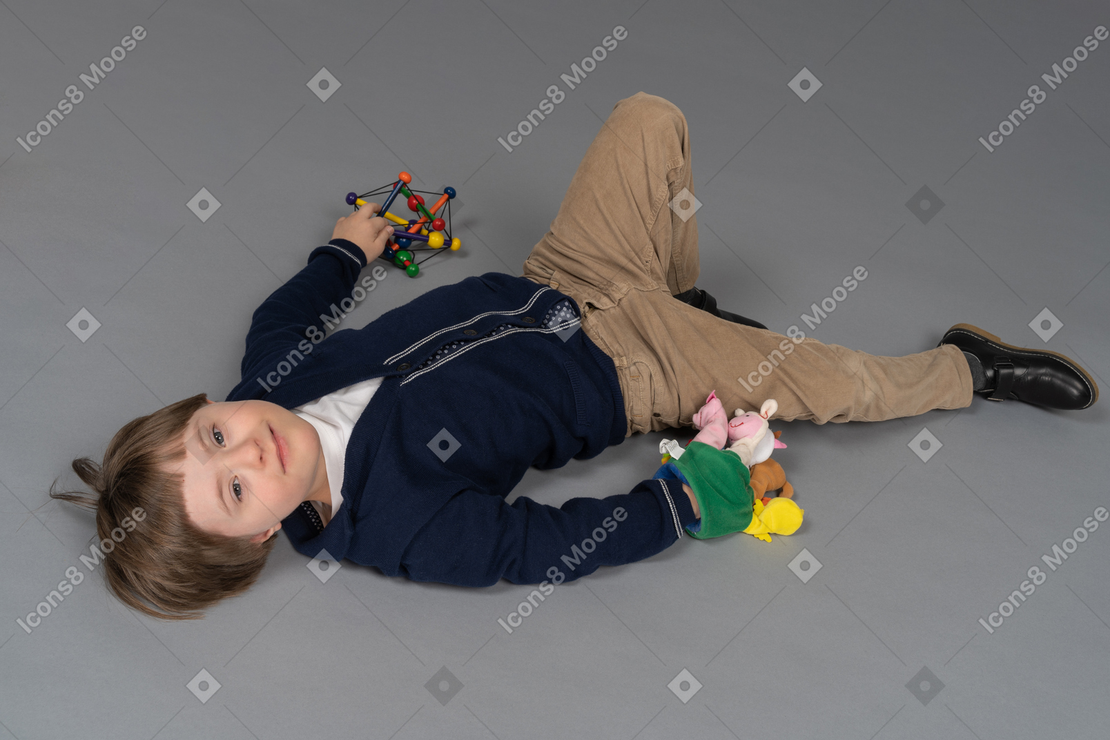 Cheerful little boy lying down with toys