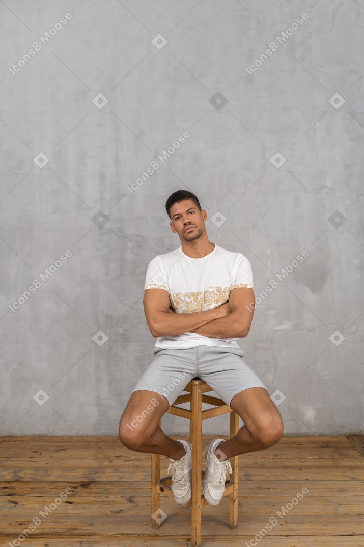 双臂交叉坐着的肌肉男的正面图