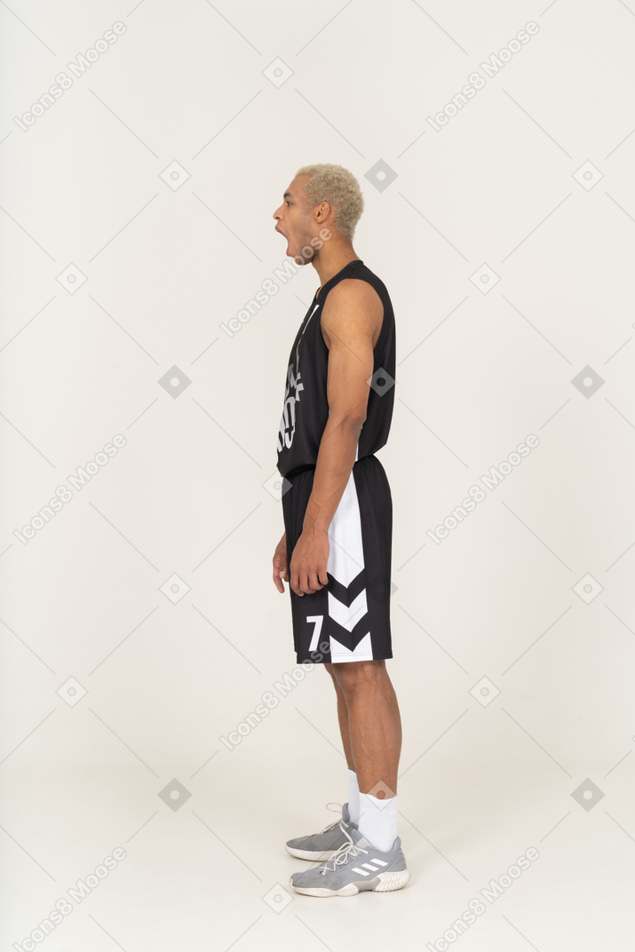 Side view of a yawning young male basketball player standing still