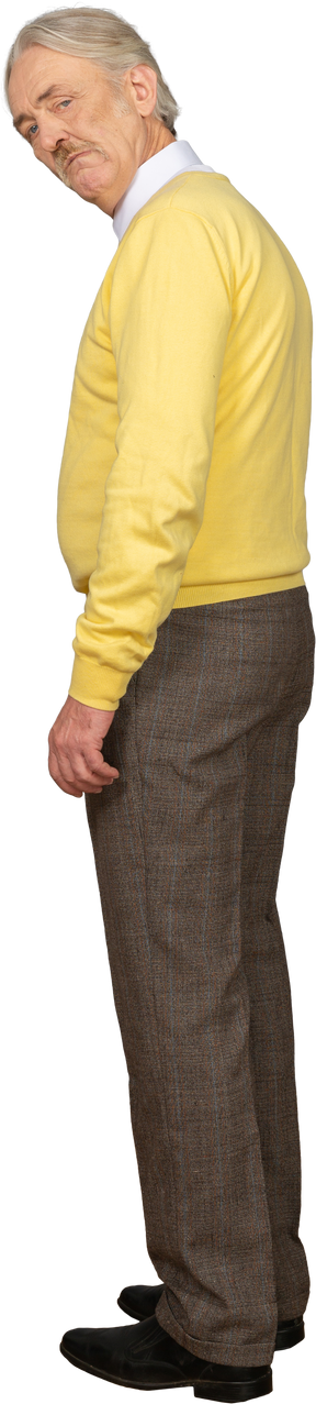 Vista lateral de un anciano sospechoso en un jersey amarillo mirando a la cámara