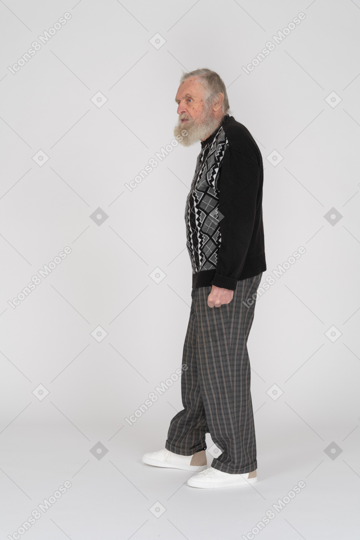 Вид в профиль на стоящего пожилого мужчину, смотрящего в сторону