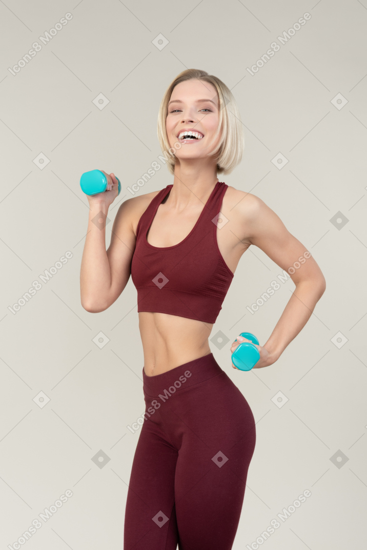 Excited young woman lifting hand weights