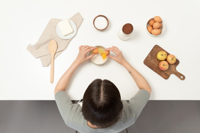 Una panadera agregando huevos a la harina