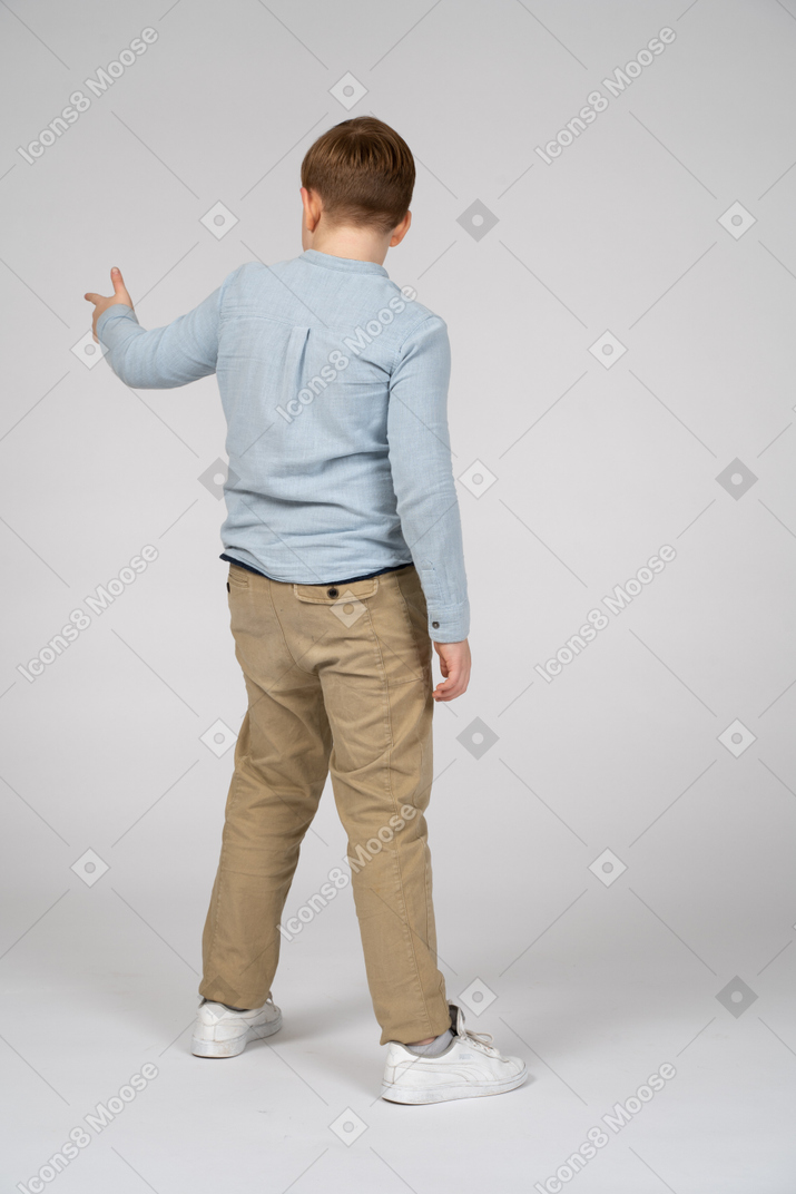 Boy standing back to camera and pointing to something