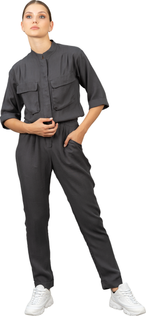Front view of a walking young woman in a jumpsuit putting hand in pocket