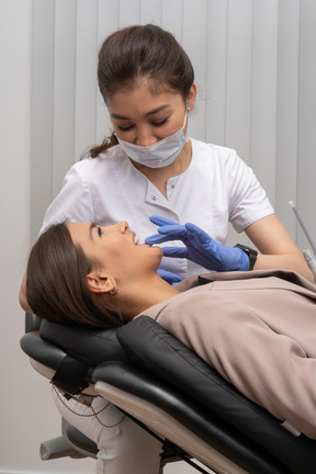 Un dentista femminile che si prende cura del suo paziente femminile sorridente