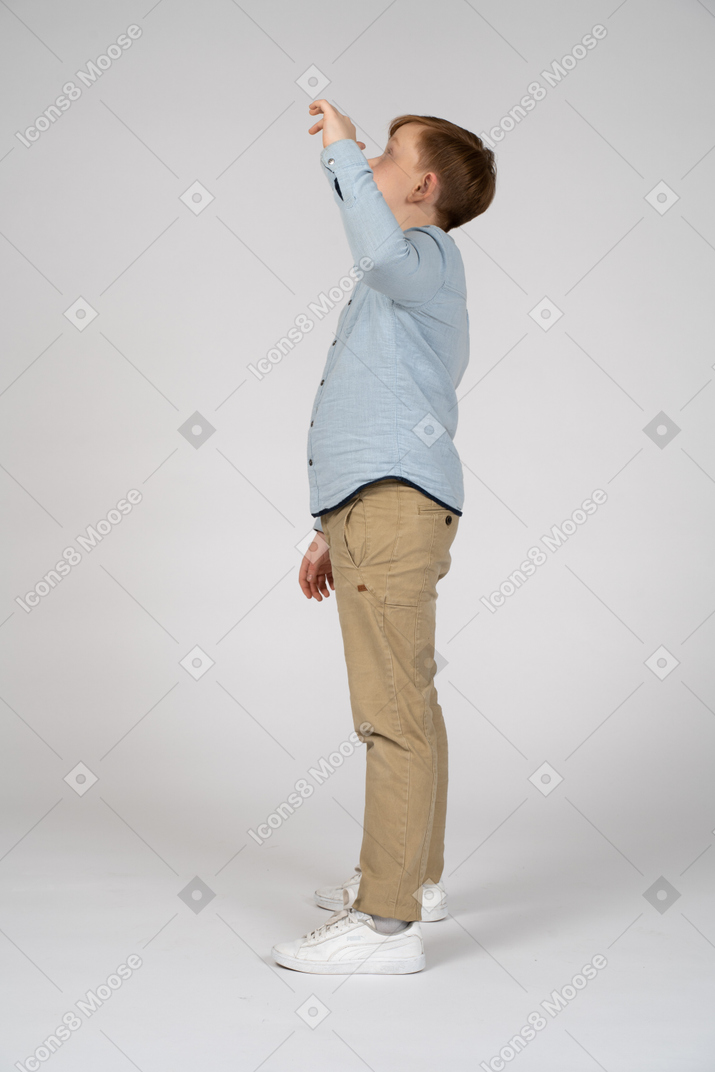Boy in blue shirt and khaki pants looking up