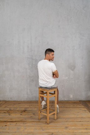 Back view of young man sitting and looking aside