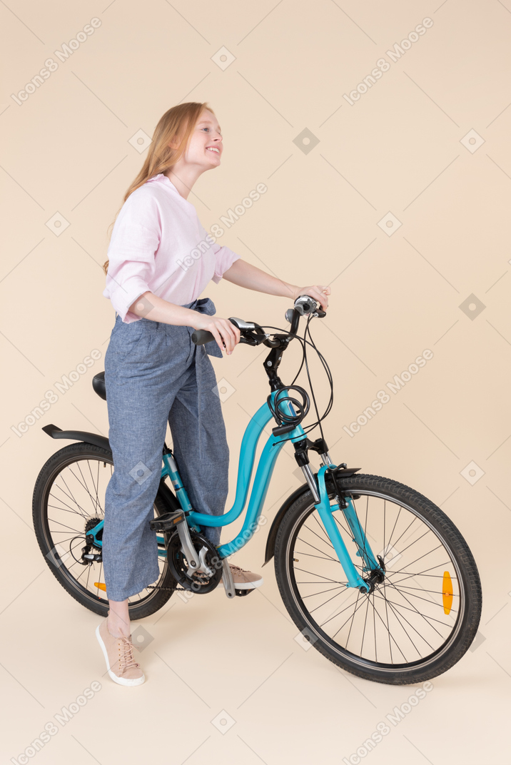 A woman standing next to a blue bicycle