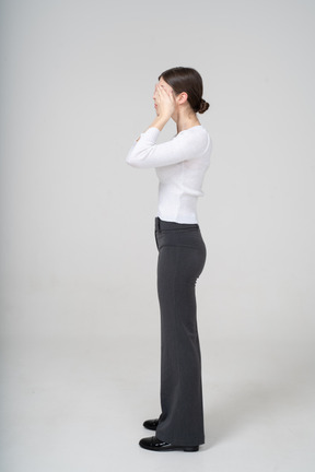 Side view of a woman in business casual clothes covering eyes with hands