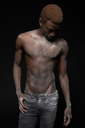 A portrait of an african man  standing with his torso all in flour