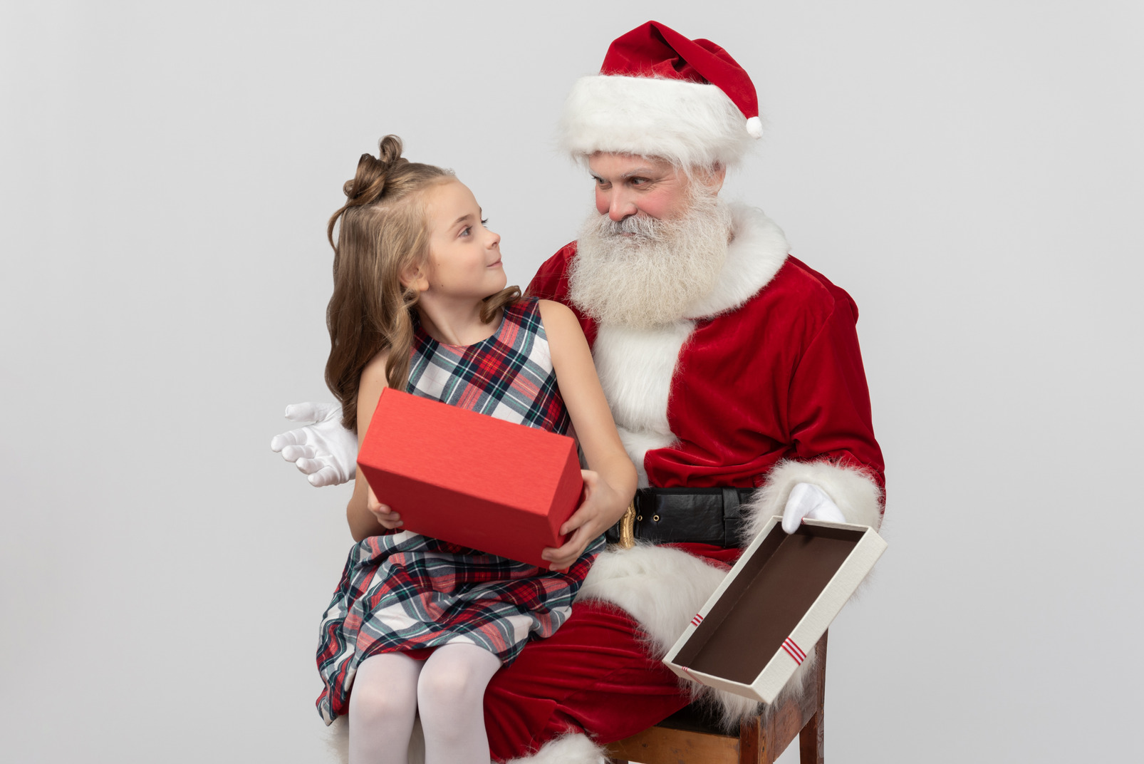 Kid girl holding empty gift box and looking at santa