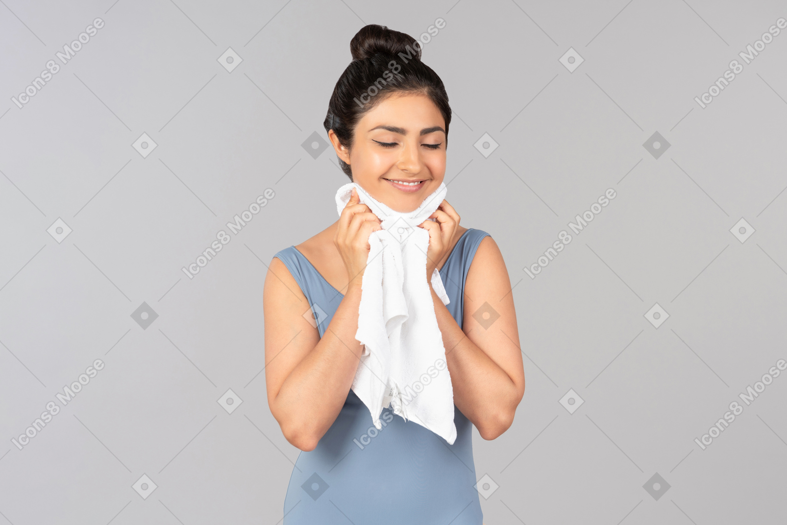 Молодая индийская женщина с закрытыми глазами сушит лицо полотенцем