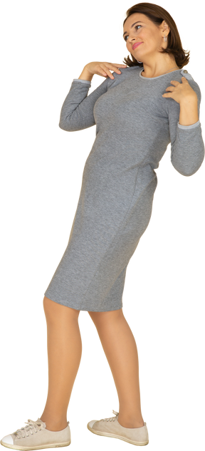 肩に手を置いて立っている灰色のドレスを着た女性の側面図