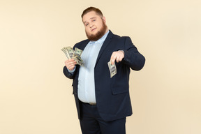 A plus-size man in a black costume with dollar bills in his hands