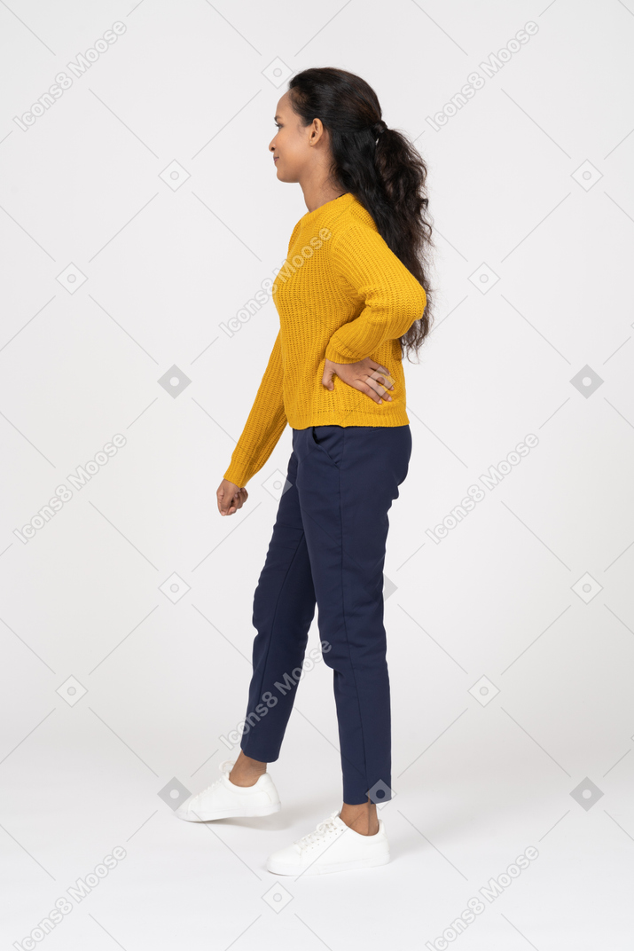 一个穿着休闲服的女孩手放在臀部摆姿势的侧视图