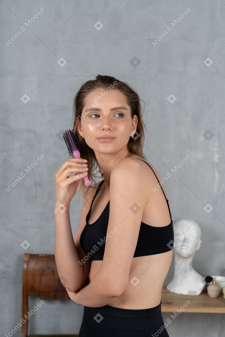 Pretty young woman holding hairbrush