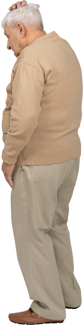 Vista lateral de un anciano con ropa informal de pie con la mano en la cabeza