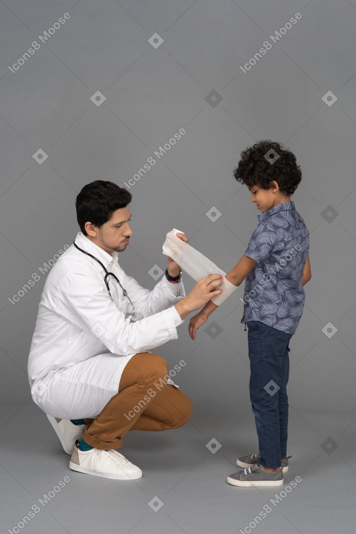 아이의 손에 붕대를 감는 의사