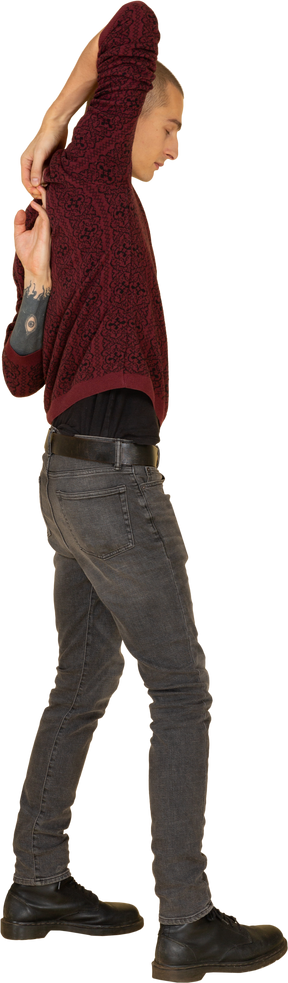 Vista laterale di un giovane uomo in pullover rosso che allunga le braccia