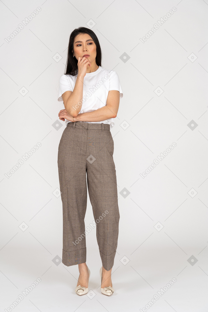 Vue de face d'une jeune femme réfléchie en culotte et t-shirt touchant le menton