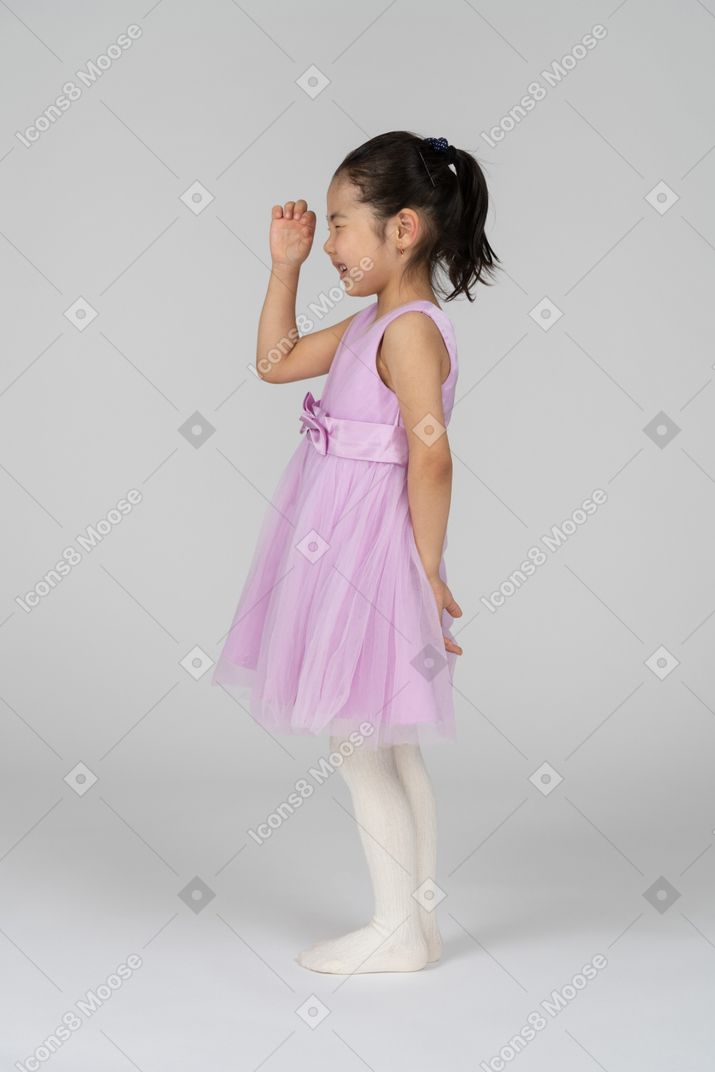 Little girl in pink dress looking through a hole made of fingers