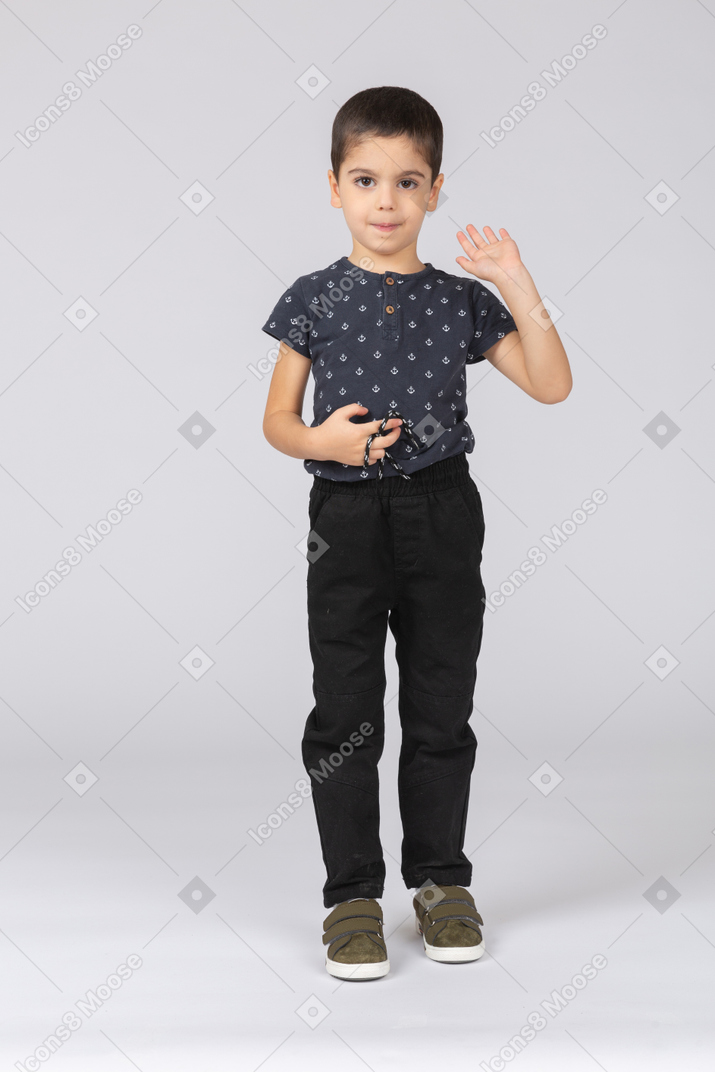 Front view of a cute boy looking at camera and waving