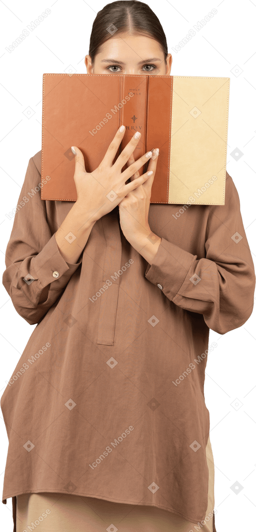 Woman covering face with a book and looking at camera