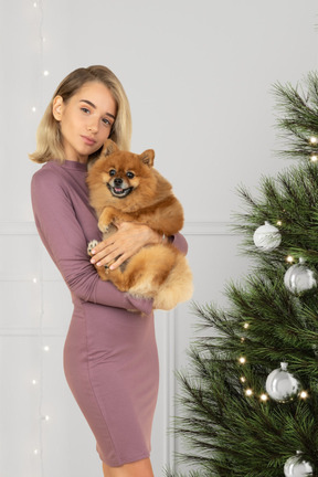 Bela jovem posando com seu cachorro para uma foto de natal