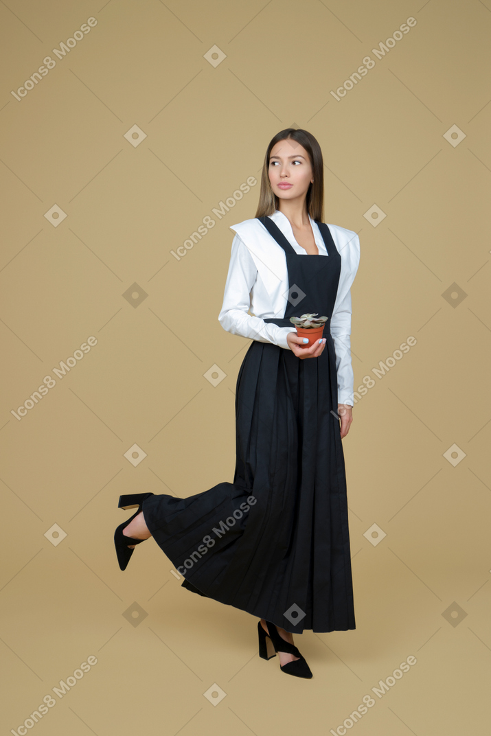 Beautiful woman in long black and white dress holding a pot
