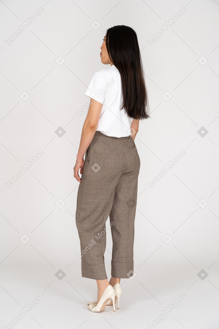 Three-quarter back view of a young woman in breeches standing still