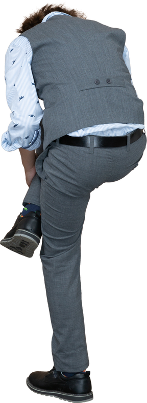 Vista posteriore di un ragazzo in abito grigio che allunga la gamba