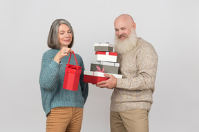 Пожилой мужчина дарит подарки элегантной зрелой женщине