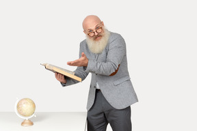 Excited old professor holding book and pointing on it