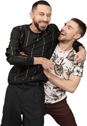Двое молодых кавказских мужчин бок о бок обнимаются и счастливо смеются