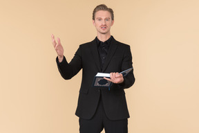 A white man in a fully black suit holding the quran