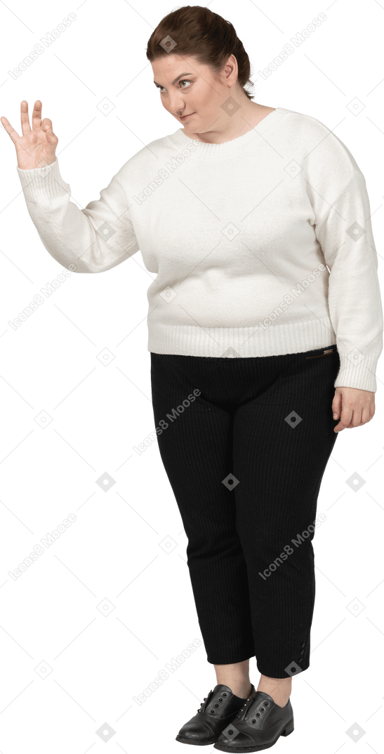 Женщина больших размеров в белом свитере показывает знак ок