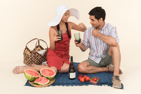 Smiling interracial couple having picnic and drinking wine