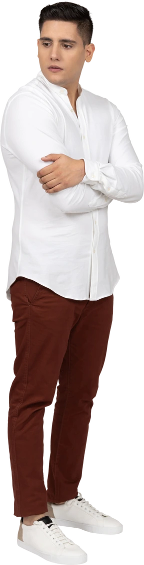 Three-quarter veiw of a young latino man holding himself and looking aside distractedly