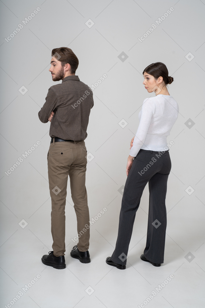 Недоверчивая молодая пара в офисной одежде, вид сзади в три четверти