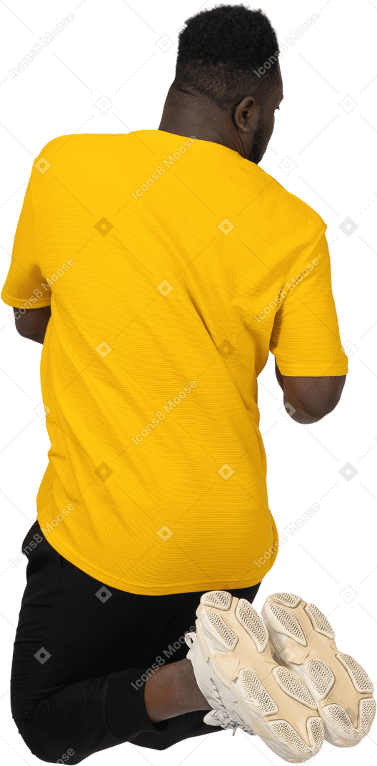 Back view of a jumping young dark-skinned man in yellow t-shirt