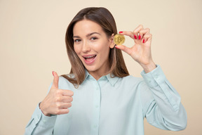 Jolie jeune fille montrant un bitcoin et le pouce en l'air