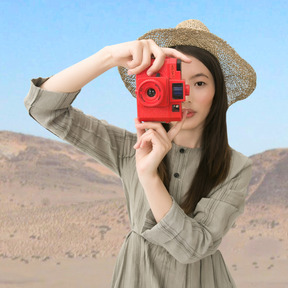 A woman in a hat holding a red camera