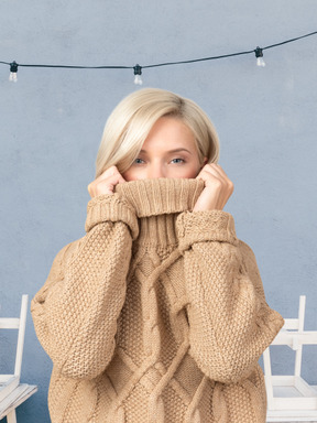 A woman putting a sweater over a half of her face