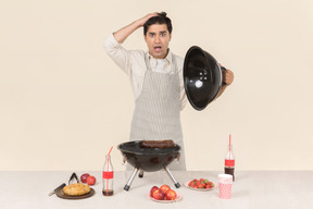 Gasping young caucasian man preparing a bbq