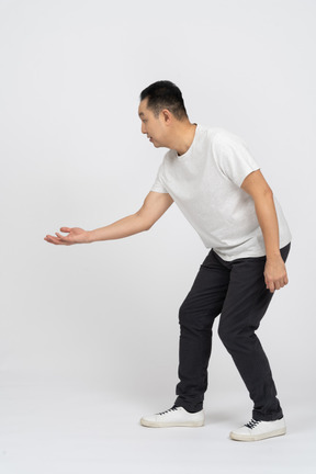 Side view of a man in casual clothes bending down with extended arm