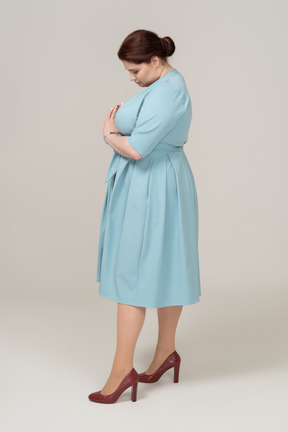 Vista laterale di una donna in abito blu che guarda in basso
